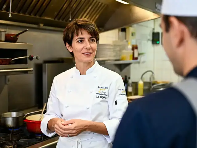 Stéphanie Le Quellec échange avec un collègue dans une cuisine professionnelle active et équipée