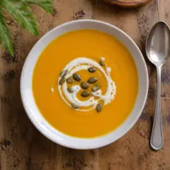 Velouté de potimarron dans une assiette creuse, graines de courge et filet de crème