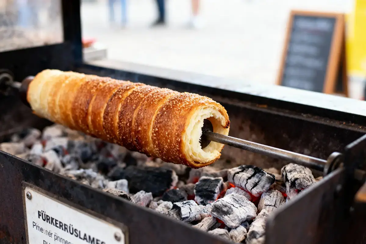 TrdelnĂk grillĂ© sur charbon de bois, avec une croĂ»te dorĂ©e et sucrĂ©e, en cuisson sur rĂ´tissoire.
