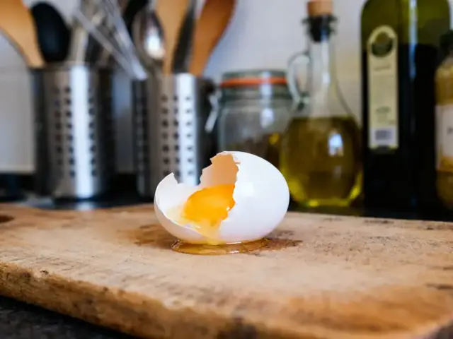 Oeuf cassé sur planche montrant le jaune combien pèse un blanc d'oeuf en cuisine