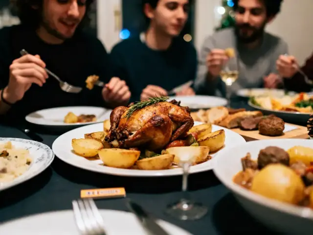 Personnes dînant autour d'un poulet rôti avec pommes de terre, partageant un repas convivial à table.