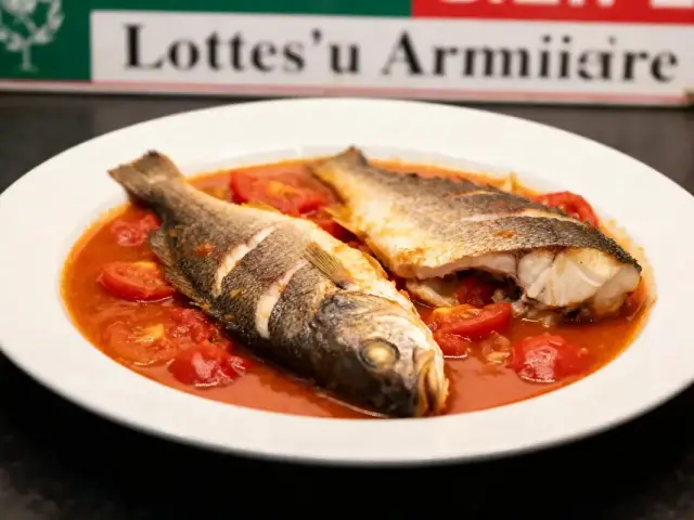 Plat de poisson entier sur sauce tomate dans une assiette blanche, avec pancarte en arrière-plan.
