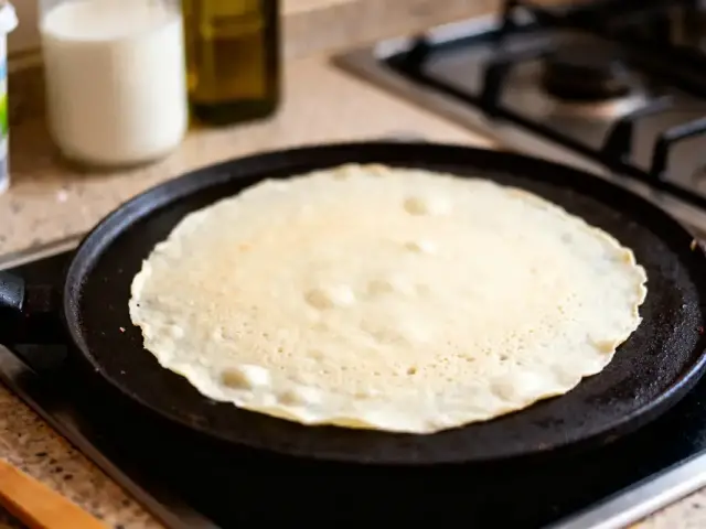 Crêpe sur une poêle chaude avec ingrédients pour recette de crêpe sans sucre en arrière-plan