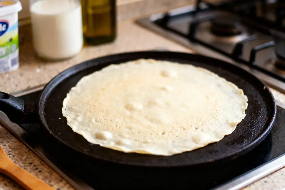 Crêpe sur une poêle chaude avec ingrédients pour recette de crêpe sans sucre en arrière-plan
