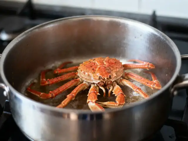 Crabe rouge dans une casserole en acier inoxydable, cuisson sur plaque de cuisson.