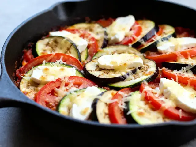 Plat de tian de légumes à l'italienne avec tomates, courgettes, aubergines et fromage fondu