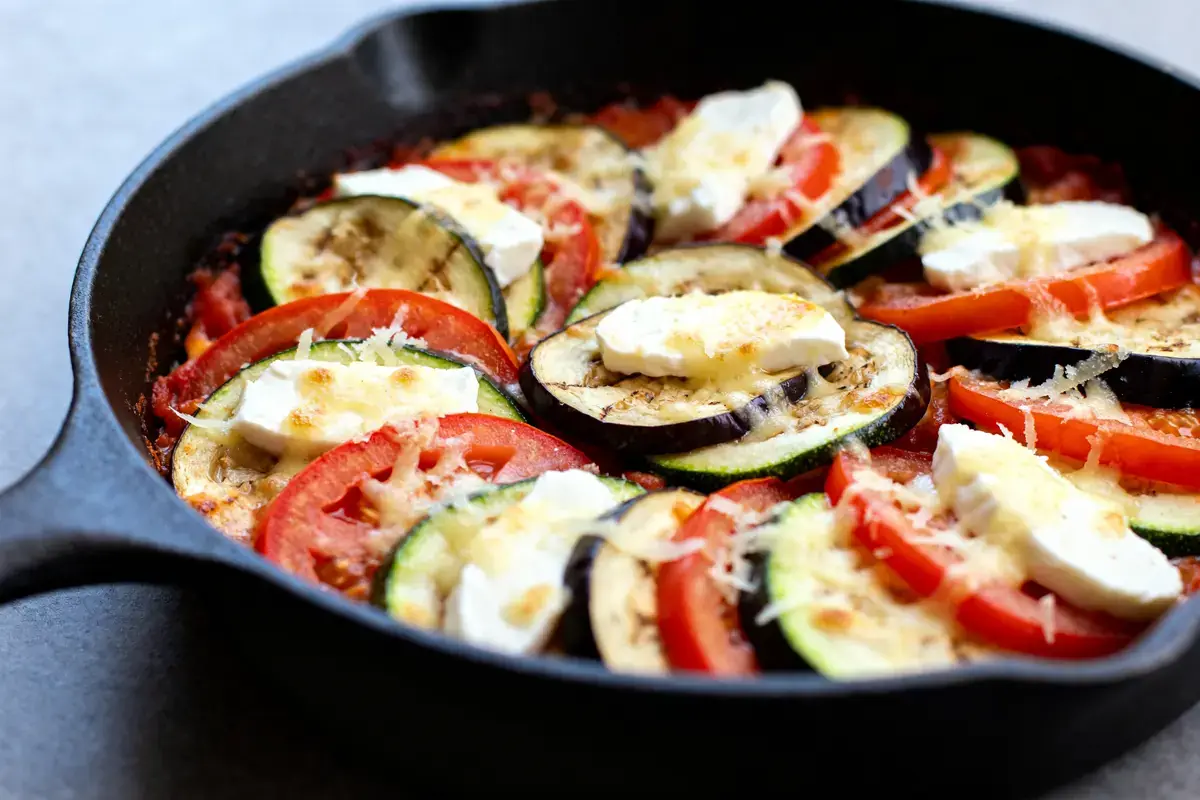 Plat de tian de légumes à l'italienne avec tomates, courgettes, aubergines et fromage fondu